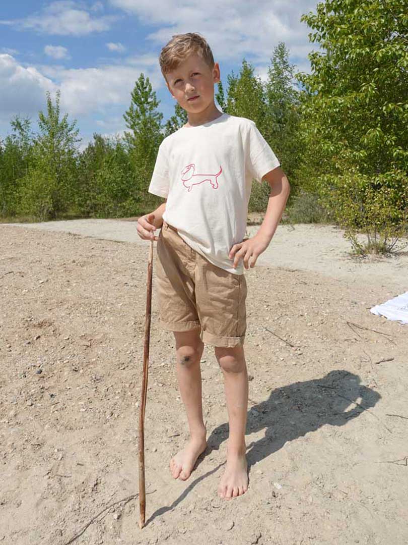 Junge am Strand mit Biobaumwoll T-Shirt roter Dackelaufdruck