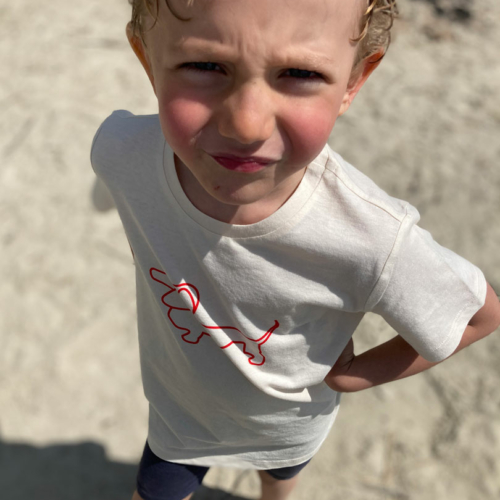 Ein Junge blinzelt bekleidet mit einem RUDIOS T-Shirt in die Sonne