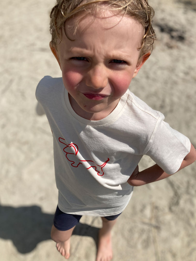 Ein Junge blinzelt bekleidet mit einem RUDIOS T-Shirt in die Sonne