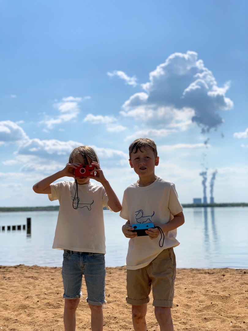 zwei Jungs fotografieren den Fotografen im Hintergrund das noch aktive Kraftwerk Espenhain
